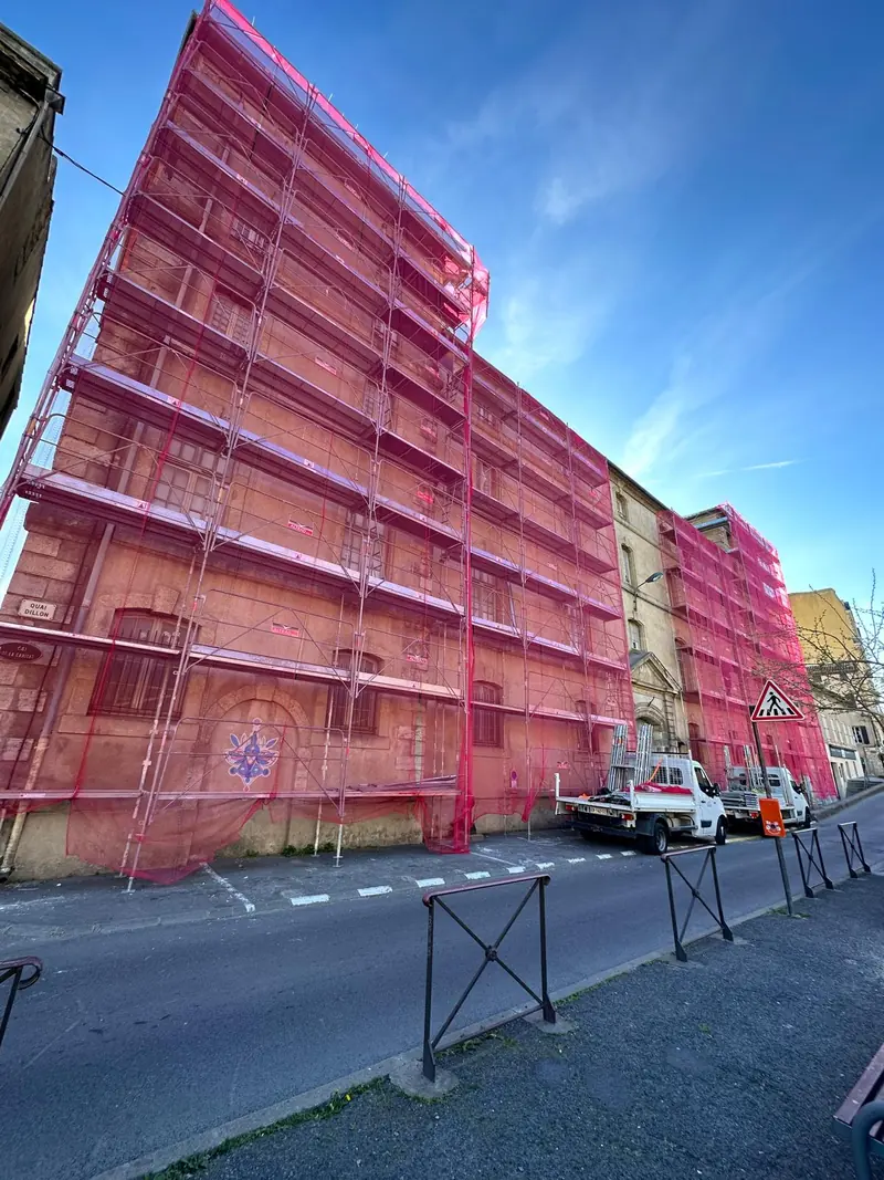 Réhabilitation de façade d'immeuble ancien sous filets de protection